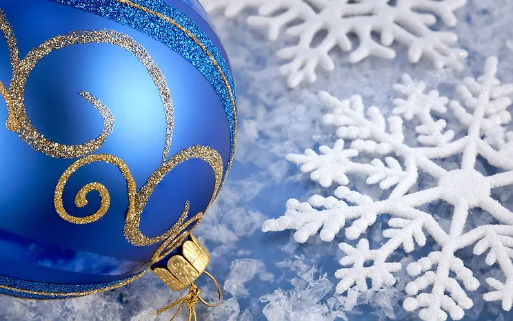 A blue and gold ornament sits beside snowflakes.