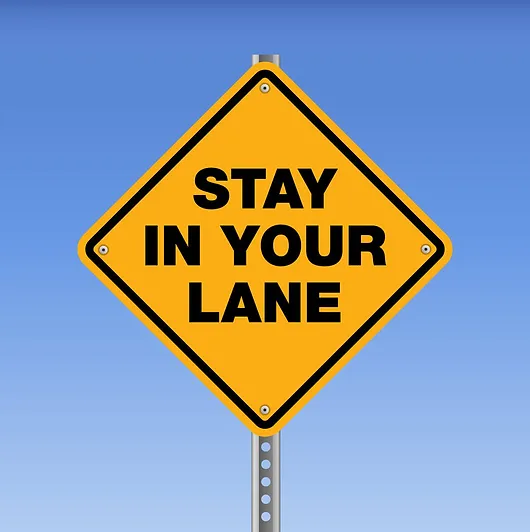 Yellow road sign that reads "Stay in your lane"