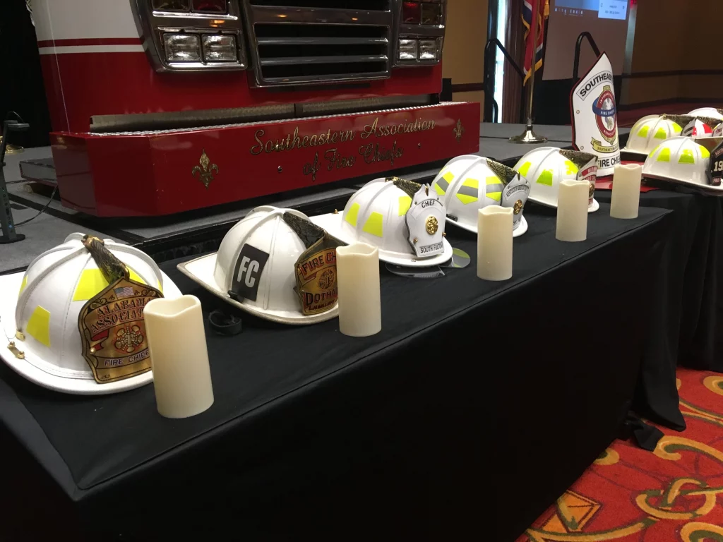 Several firefighter hats rest on a table beside candles.