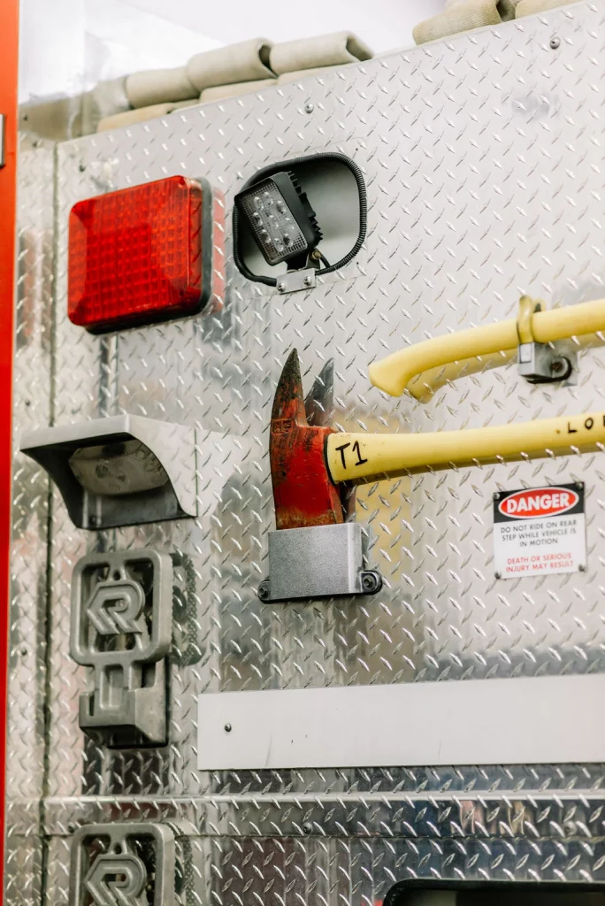 Firefighter tools including a fire axe hang in their places on the back of a fire truck.